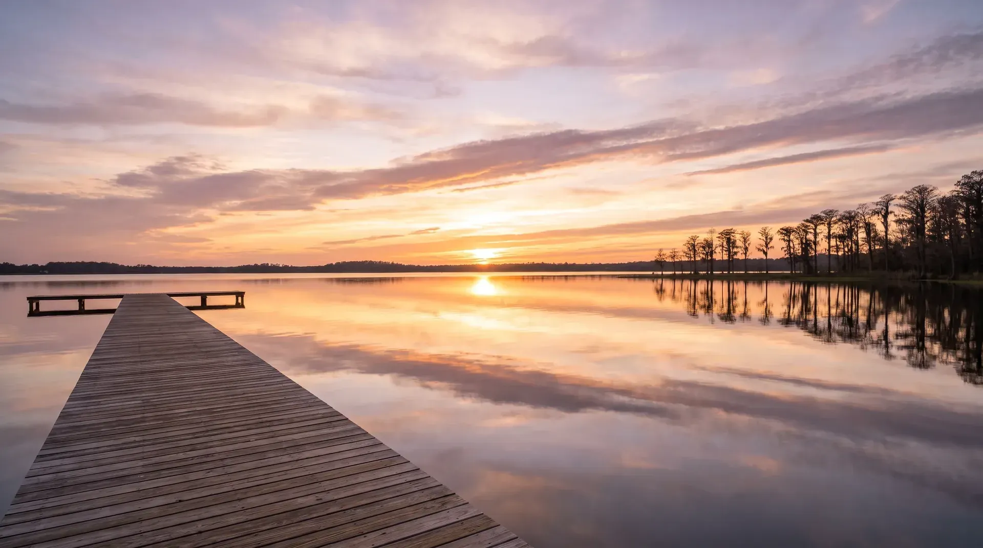 A long wooden pier on a calm lake at sunset