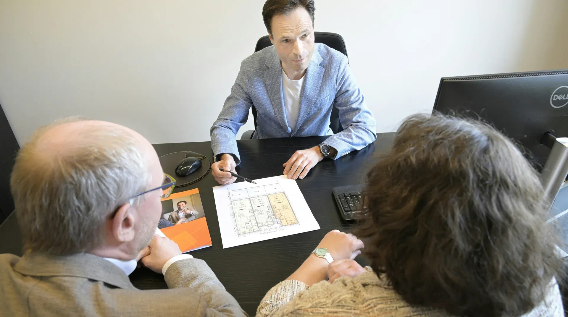 An advisor walking a couple through business plans at an office desk
