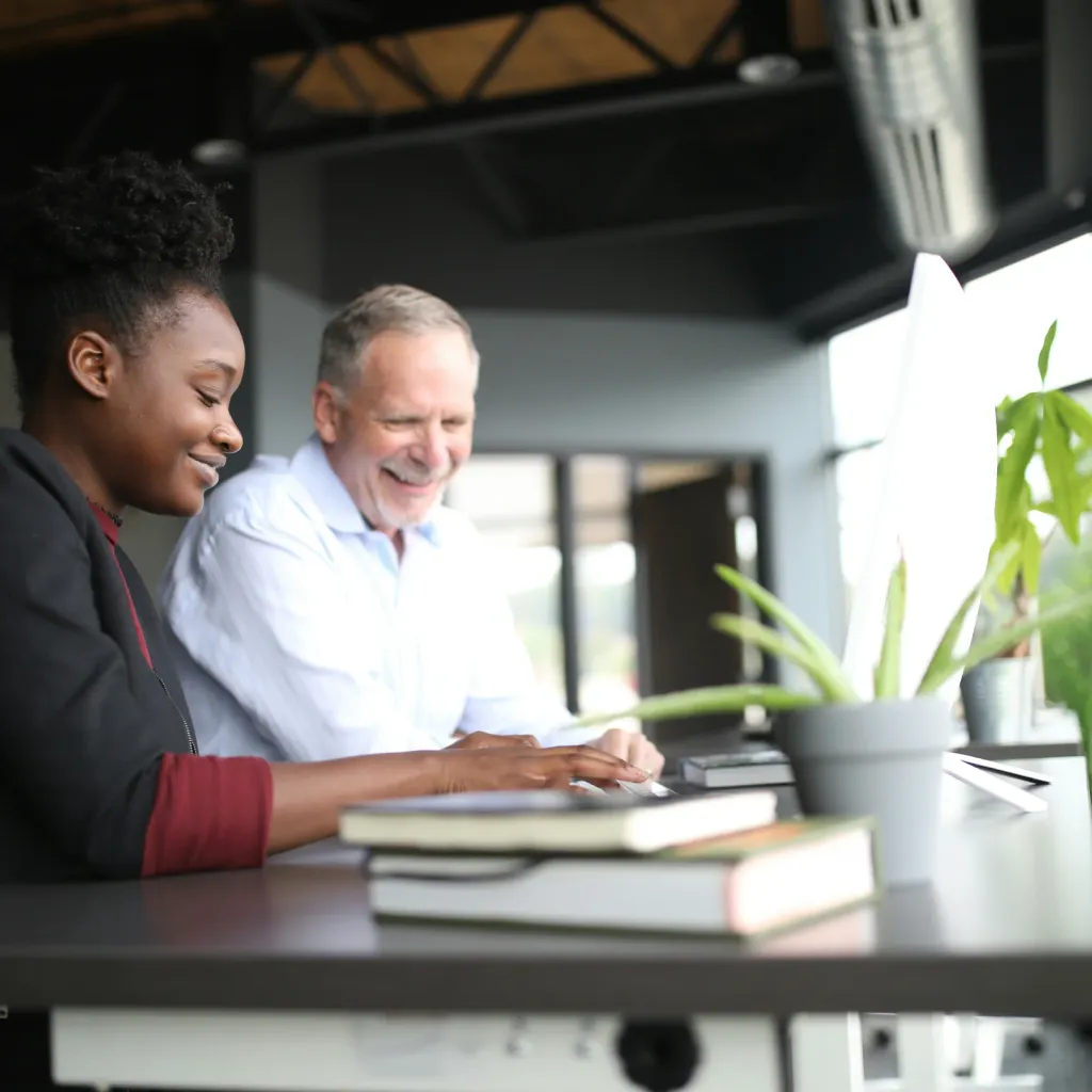 An experienced business owner and a younger colleague working together at an office desk