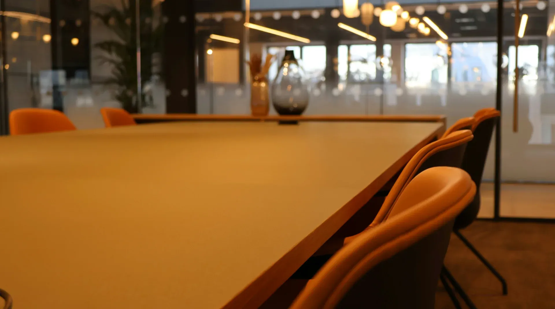 A warm, modern conference room with a long table and orange chairs