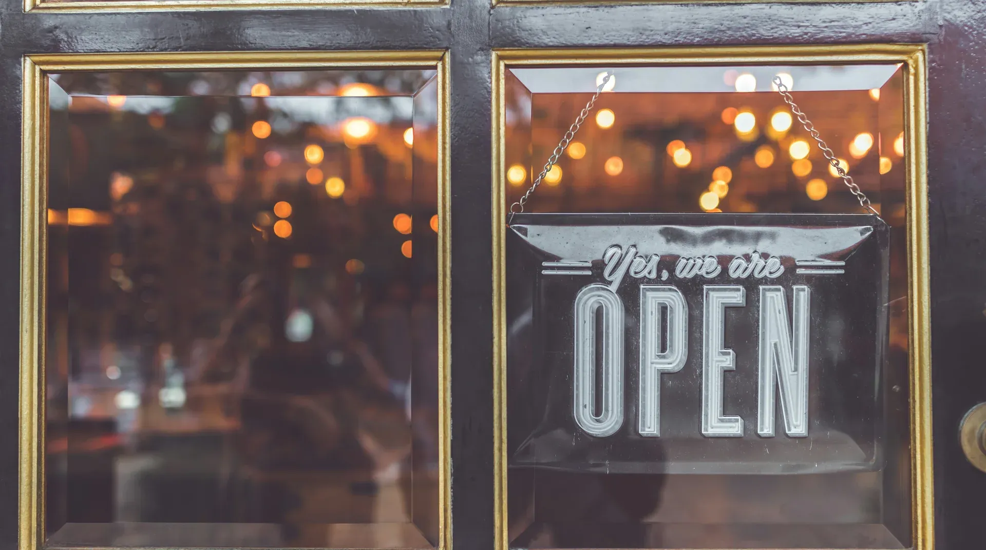 An Open sign hanging on the glass door of a small business